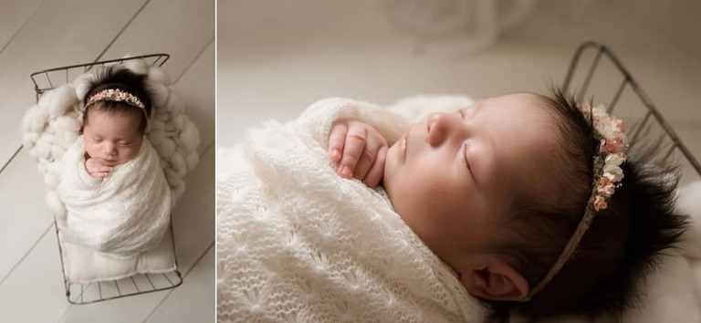 Baby girl wrapped in white on metal bed with white floors.