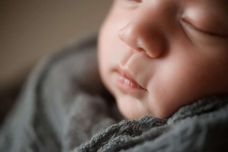 Closeup macro of newborn girl in gray
