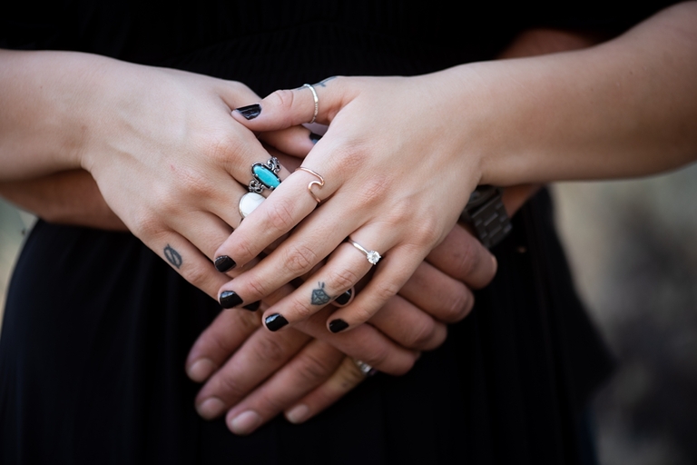 Engagement photo of fiancé's hands embracing, rings and tattoos