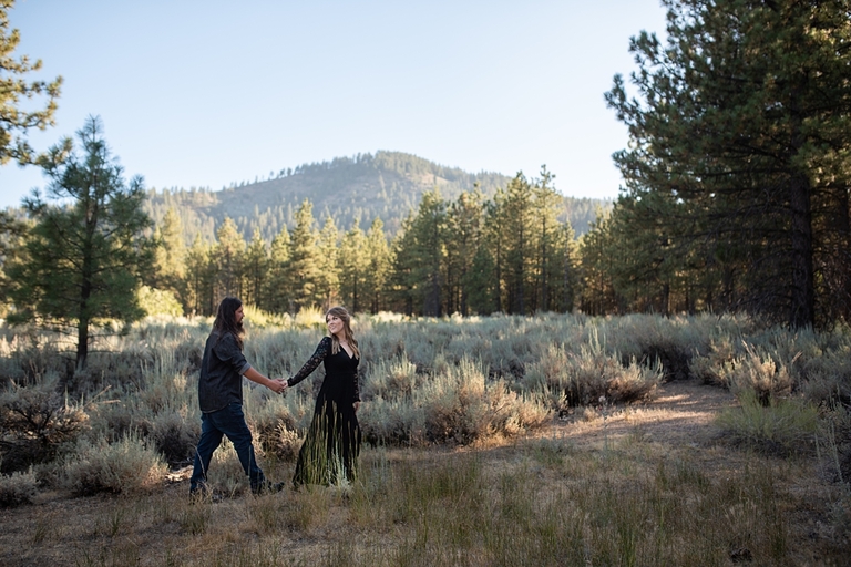 Couple standing in front of forest embracing for engagement photos